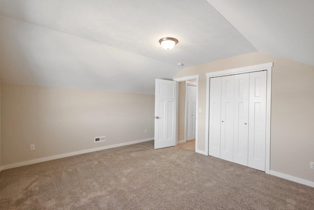 bonus room with a textured ceiling, light carpet, and vaulted ceiling