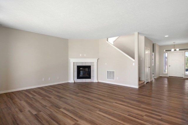 unfurnished living room featuring a textured ceiling, a tile fireplace, and dark hardwood / wood-style floors