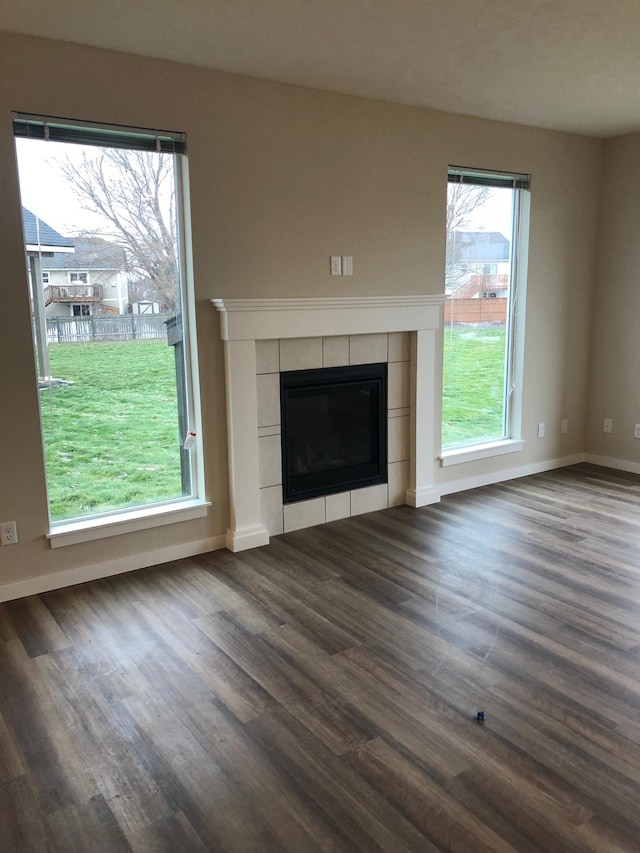 unfurnished living room featuring dark hardwood / wood-style flooring and a tiled fireplace