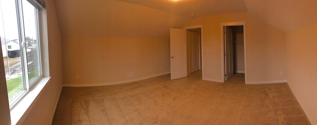 carpeted empty room with vaulted ceiling