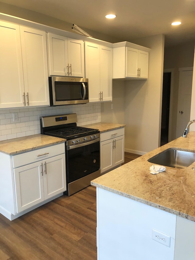 kitchen featuring stainless steel appliances, dark wood-type flooring, white cabinets, sink, and light stone countertops