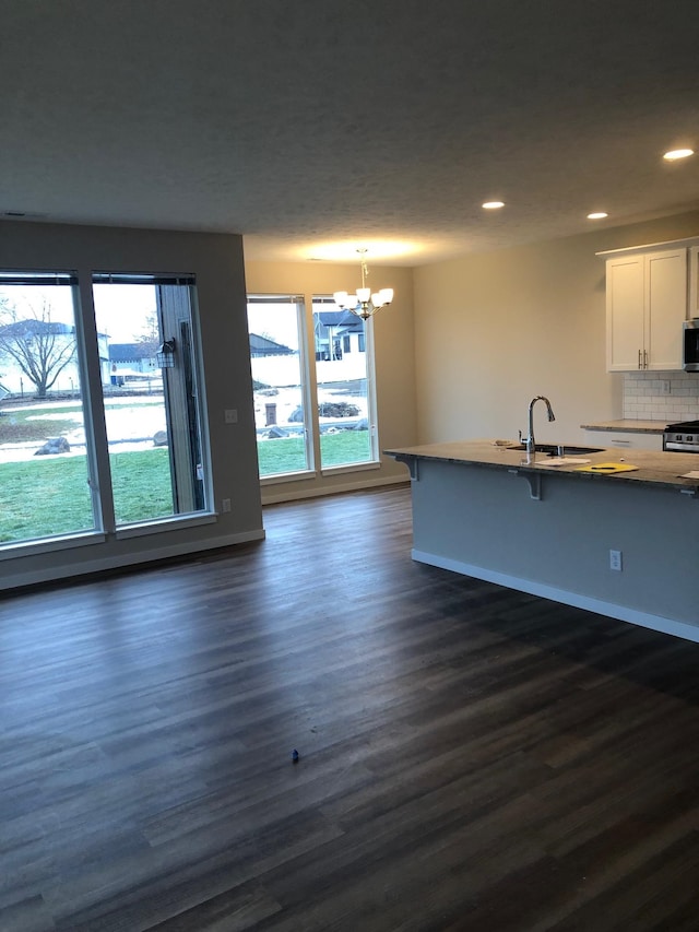 kitchen with white cabinetry, a breakfast bar, backsplash, pendant lighting, and dark hardwood / wood-style flooring