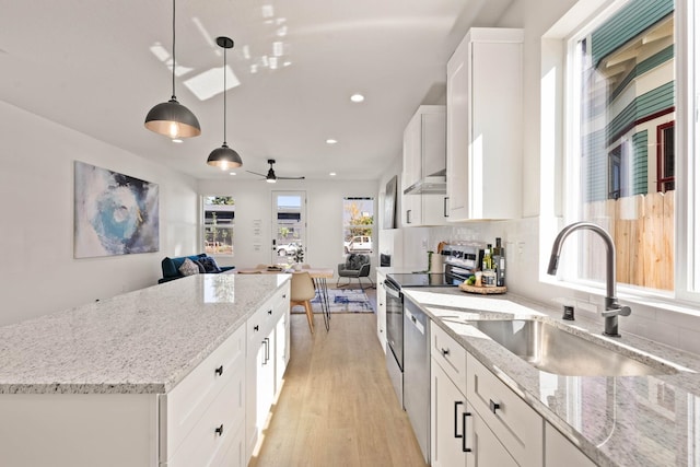 kitchen featuring decorative backsplash, sink, white cabinetry, light hardwood / wood-style flooring, and decorative light fixtures