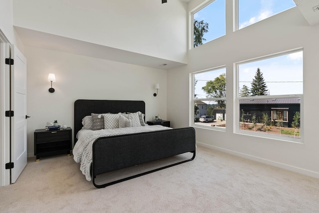 bedroom with a towering ceiling and light carpet