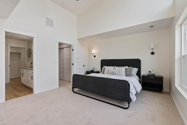 carpeted bedroom featuring connected bathroom, a closet, and a towering ceiling