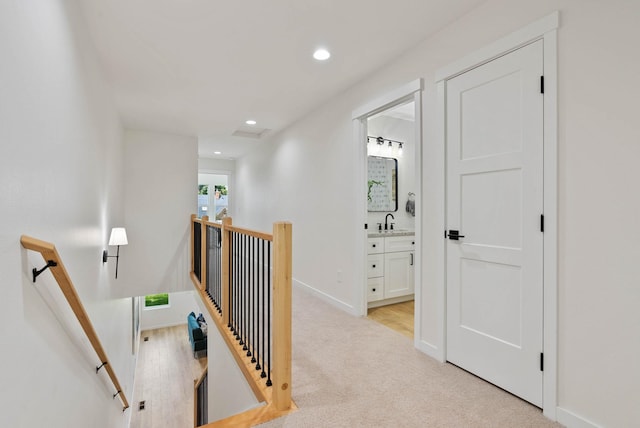 hallway with light colored carpet and sink