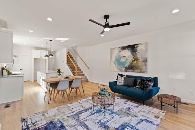 living room with ceiling fan, sink, and light hardwood / wood-style flooring