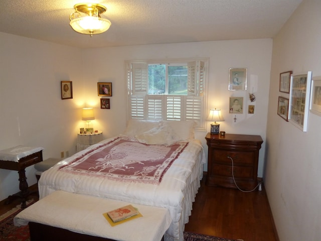 bedroom featuring a textured ceiling and dark hardwood / wood-style flooring