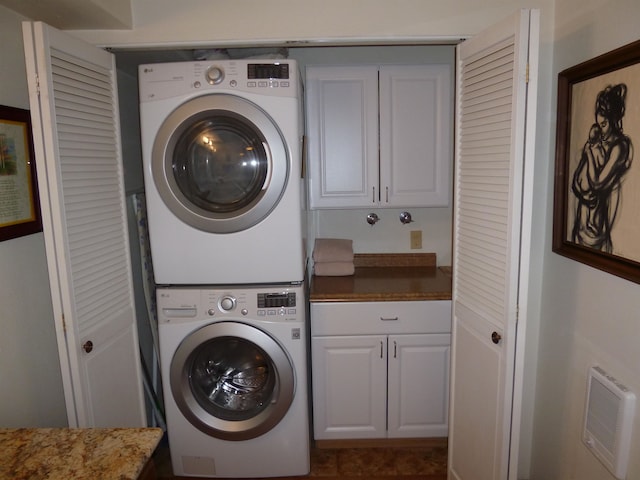 laundry area with cabinets and stacked washer and clothes dryer