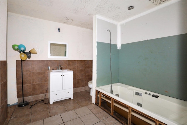 bathroom with a bath, tile patterned flooring, tile walls, toilet, and vanity