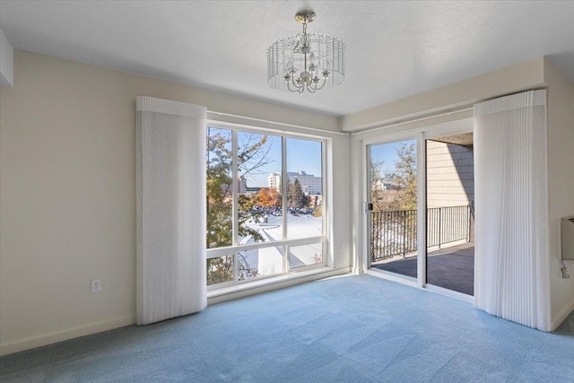 unfurnished dining area with carpet, an inviting chandelier, and a textured ceiling