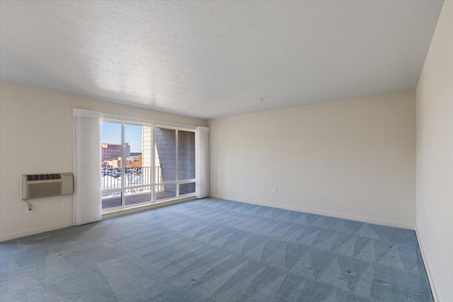 carpeted empty room with a wall unit AC and a textured ceiling