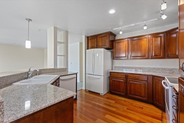 kitchen with light hardwood / wood-style floors, light stone counters, sink, pendant lighting, and white appliances