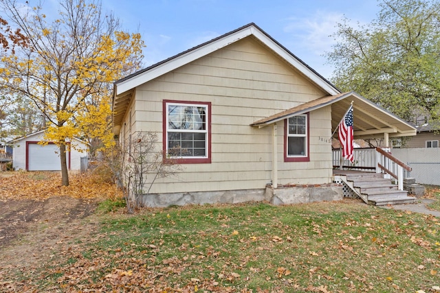 bungalow-style house featuring a garage, an outdoor structure, and a front yard