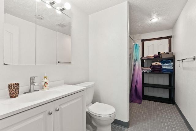 bathroom with walk in shower, vanity, a textured ceiling, tile patterned flooring, and toilet