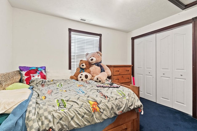 bedroom with dark colored carpet, a closet, and a textured ceiling