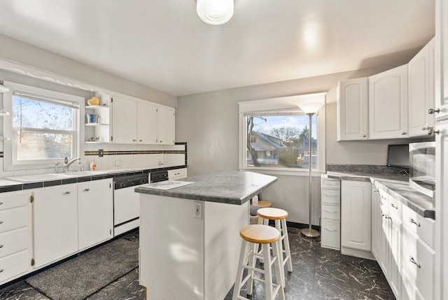 kitchen with plenty of natural light, white cabinets, white dishwasher, and a center island