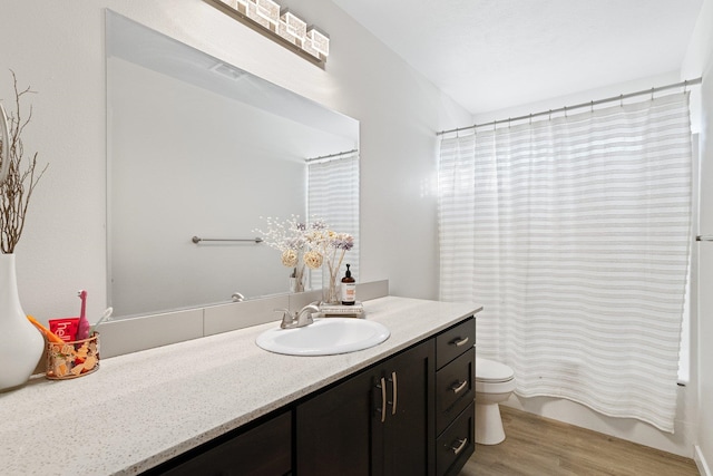 full bathroom featuring hardwood / wood-style flooring, vanity, toilet, and shower / bath combo