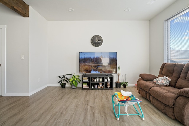 living room featuring beamed ceiling and light hardwood / wood-style flooring