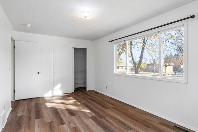 unfurnished bedroom featuring a closet, wood finished floors, visible vents, and baseboards