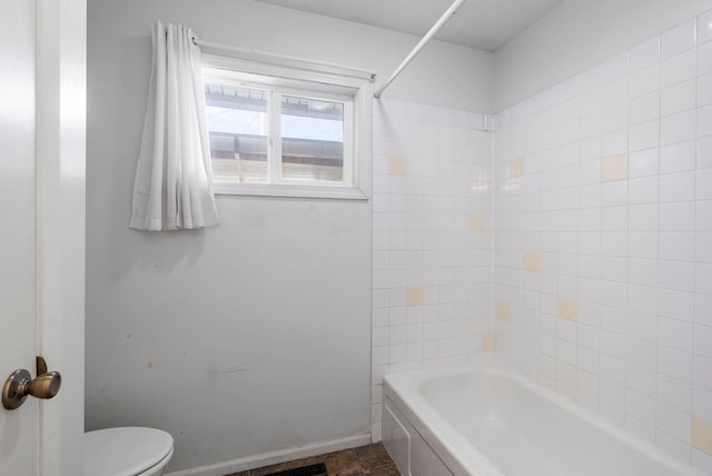 full bath featuring toilet, baseboards, and  shower combination