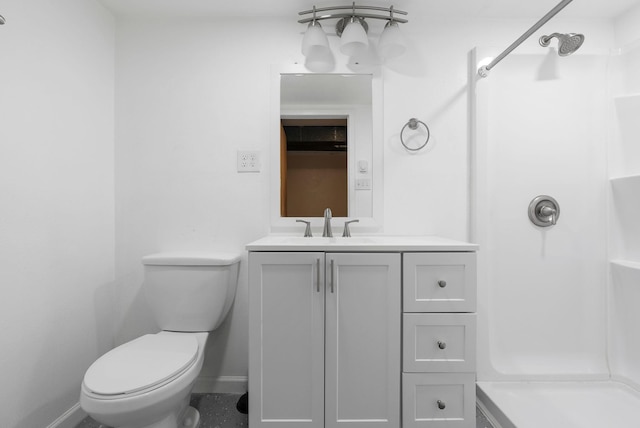 bathroom featuring toilet, a shower, vanity, and baseboards