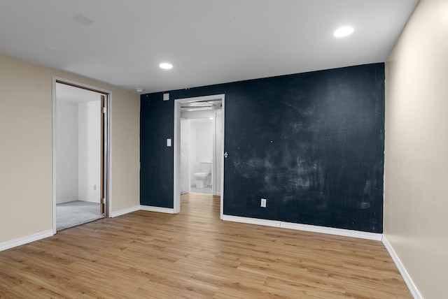 spare room featuring light wood-style flooring, baseboards, and recessed lighting