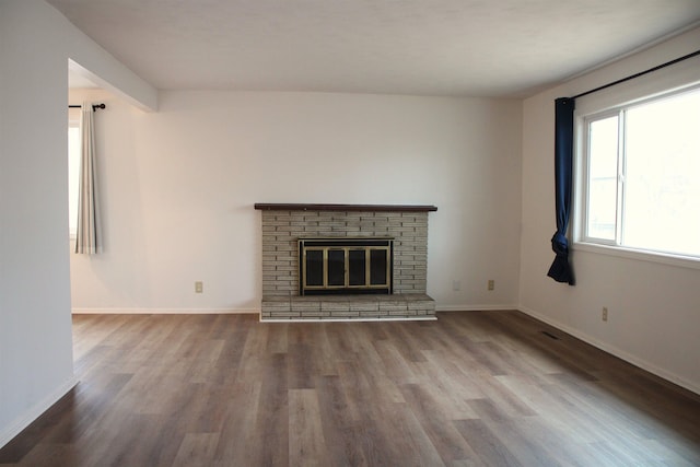 unfurnished living room with a fireplace, baseboards, and wood finished floors