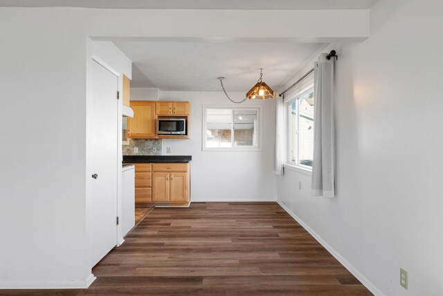 kitchen with tasteful backsplash, baseboards, dark wood finished floors, stainless steel microwave, and light brown cabinetry