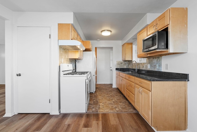 kitchen featuring stainless steel microwave, decorative backsplash, white range with gas cooktop, a sink, and under cabinet range hood