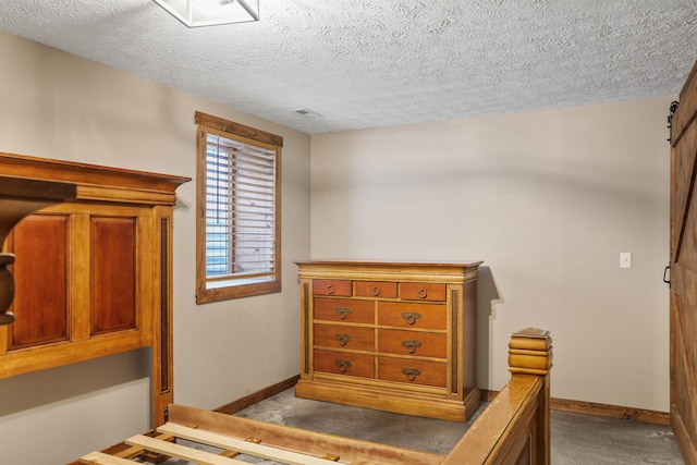 carpeted bedroom featuring a barn door and a textured ceiling