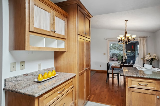 kitchen with dark stone counters, hardwood / wood-style floors, a chandelier, pendant lighting, and vaulted ceiling