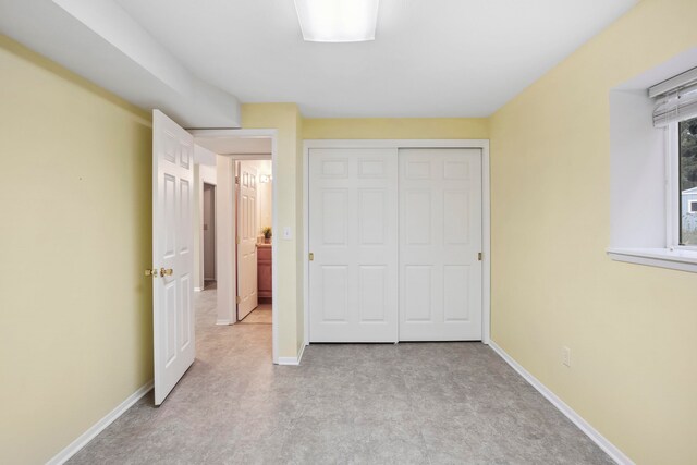 unfurnished bedroom with a closet and light colored carpet