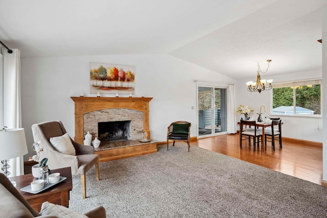 living room featuring wood-type flooring, an inviting chandelier, lofted ceiling, and a high end fireplace