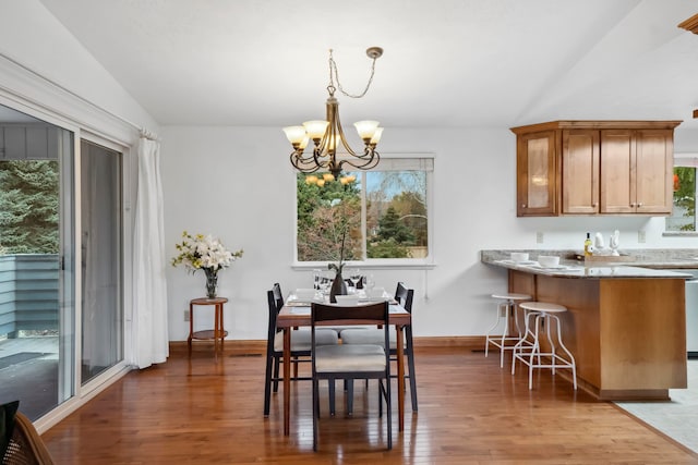 dining space featuring a wealth of natural light, a notable chandelier, dark hardwood / wood-style floors, and vaulted ceiling