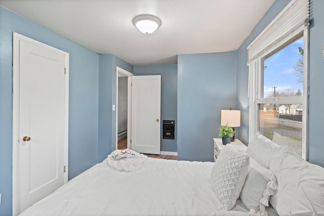 bedroom featuring hardwood / wood-style floors and a baseboard heating unit