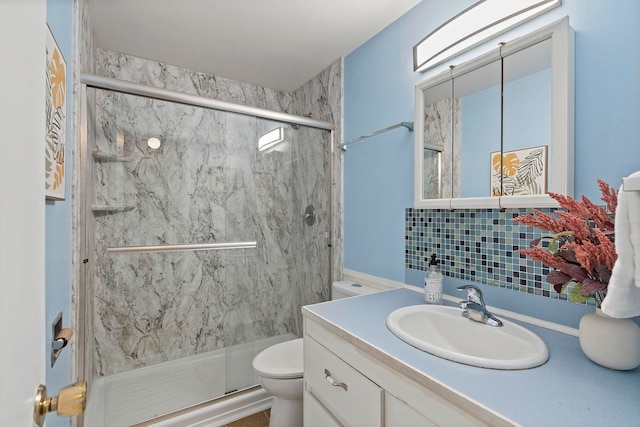 bathroom with backsplash, vanity, a shower with shower door, and toilet