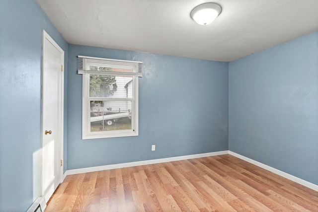 empty room featuring baseboard heating and light hardwood / wood-style floors