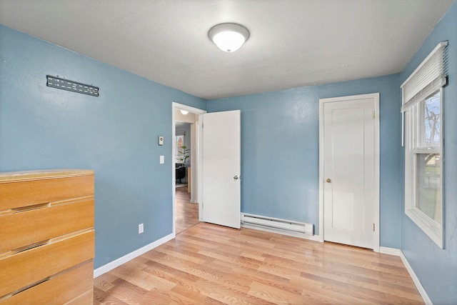 unfurnished bedroom featuring light hardwood / wood-style flooring and baseboard heating