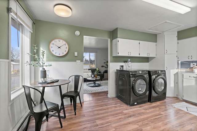 laundry room with cabinets, washing machine and dryer, light hardwood / wood-style floors, and baseboard heating