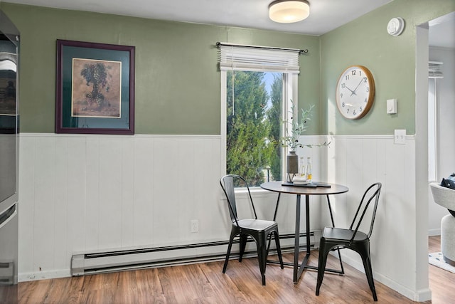 dining room with wood-type flooring, plenty of natural light, and a baseboard heating unit