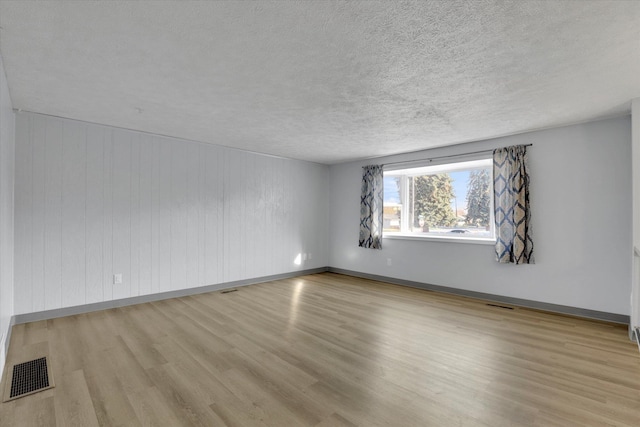 spare room with a textured ceiling and light hardwood / wood-style floors