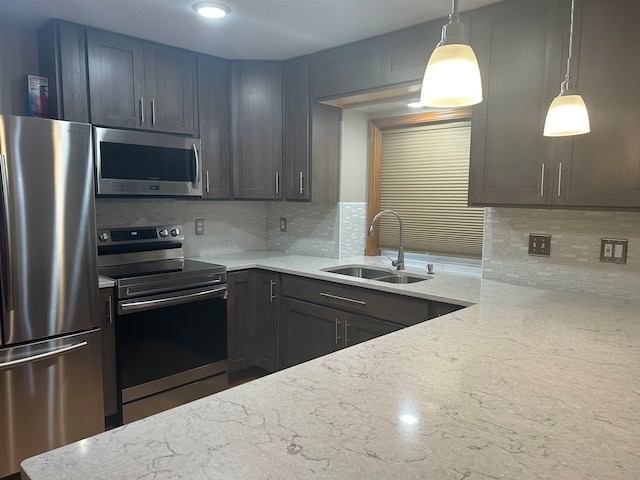 kitchen with light stone counters, backsplash, appliances with stainless steel finishes, hanging light fixtures, and sink