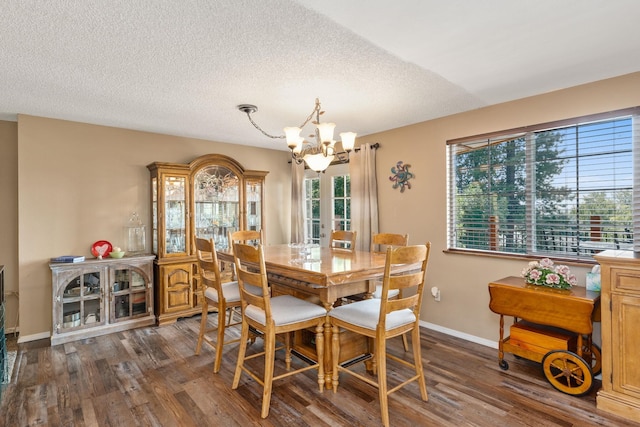 dining area featuring a textured ceiling, a notable chandelier, and dark wood-type flooring