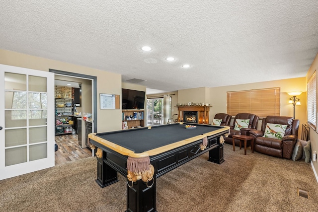 rec room with light colored carpet, a textured ceiling, and a wealth of natural light