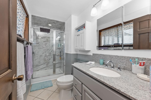 bathroom with tile patterned floors, vanity, a shower with shower door, and toilet