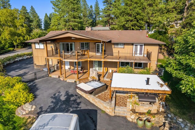 view of front of home with french doors, a balcony, a hot tub, and a deck