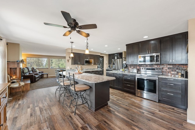 kitchen with stainless steel appliances, dark hardwood / wood-style flooring, decorative light fixtures, a breakfast bar area, and decorative backsplash