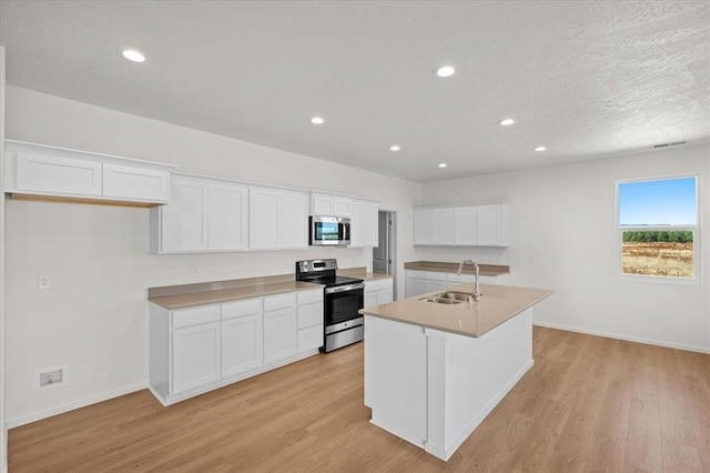 kitchen with a center island with sink, white cabinets, stainless steel appliances, and sink