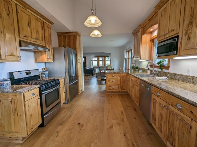 kitchen featuring kitchen peninsula, appliances with stainless steel finishes, sink, decorative light fixtures, and light hardwood / wood-style floors